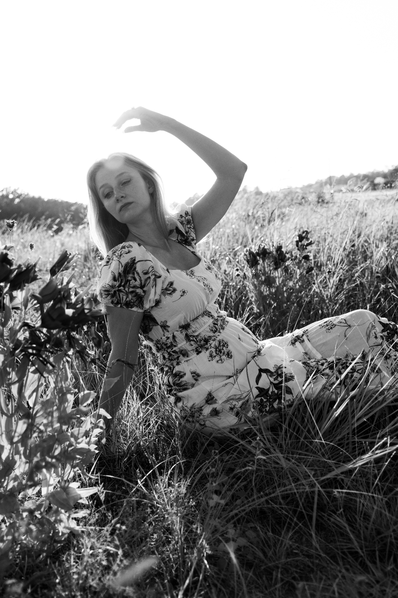 Naomi in a wildflower field, arm raised into the sun