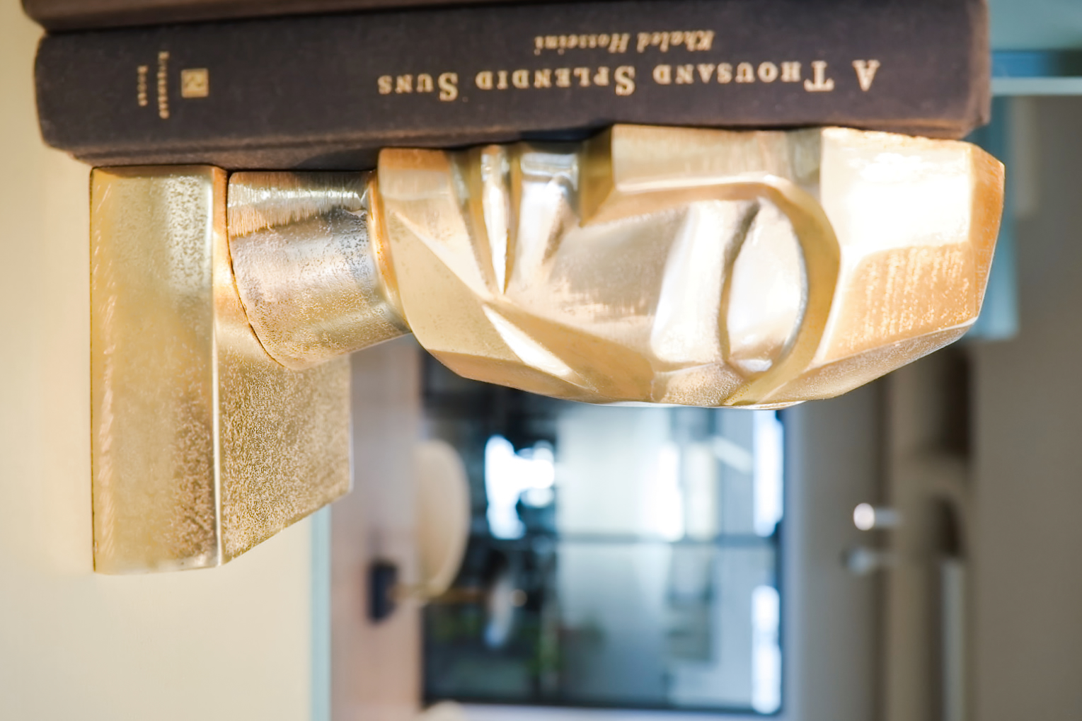 Brass sculptural bookend on a shelf