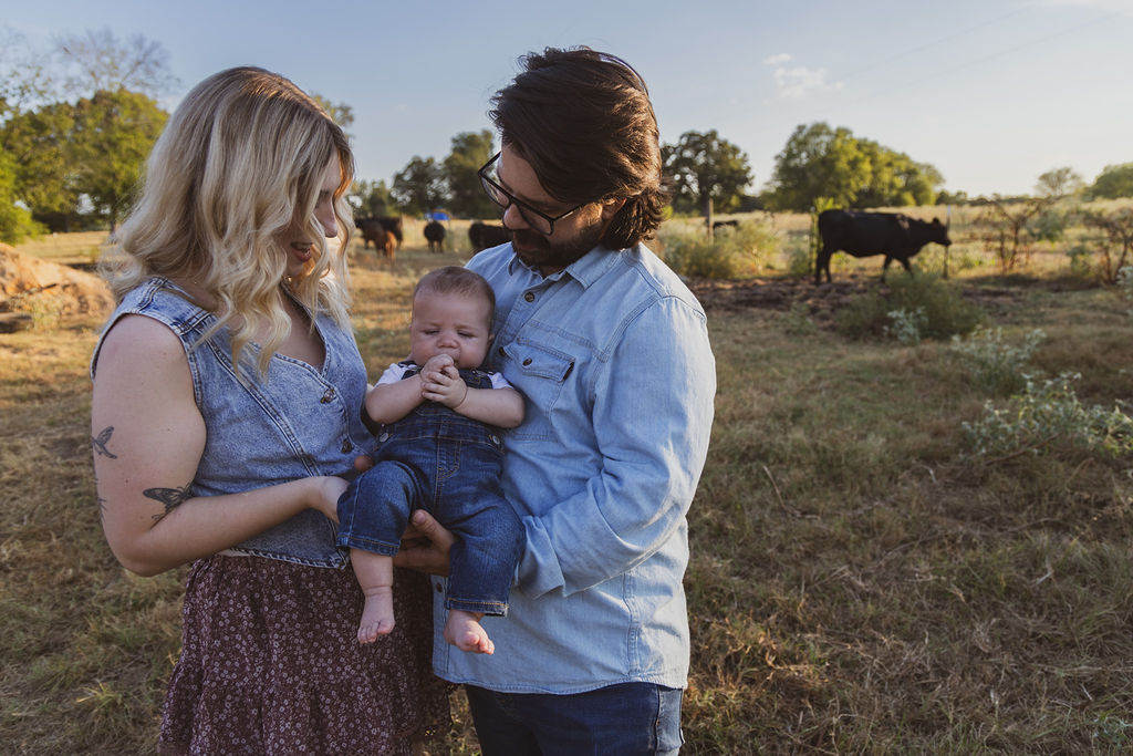 Family holding their baby in a sunlit field